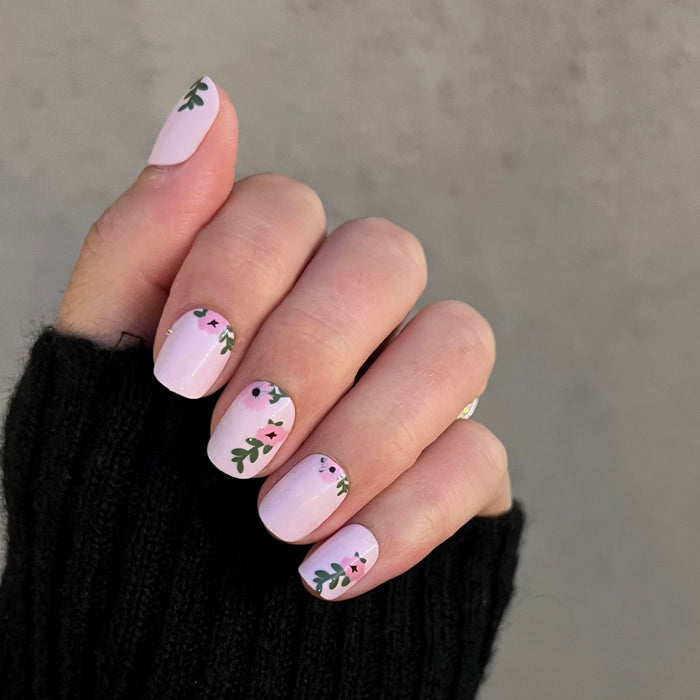 Wild Bouquet - Press-On | Short | Squoval short nails with soft pink base and delicate green leafy floral accents on hand in black sleeve