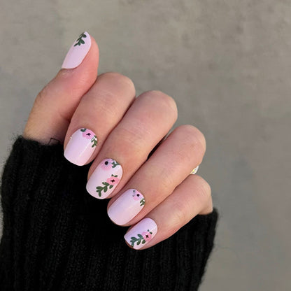 Wild Bouquet - Press-On | Short | Squoval short nails with soft pink base and delicate green leafy floral accents on hand in black sleeve