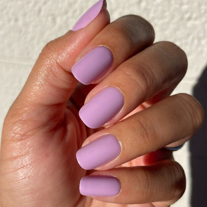 Close-up of hand with You're Invited - Press-On | Short | Squoval showing short squoval nails in playful lilac polish manicure